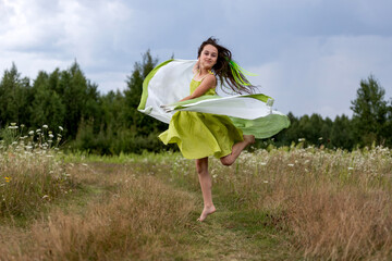 young woman dancing barefoot on the field in a green dress