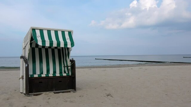 ein leerer Strandkorb steht im Sand am Meer
