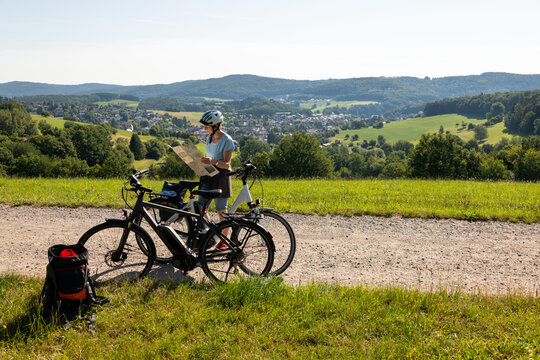 Fahrrad Fahrerin studiert Landkarte, Ausflug mit Elektro Fahrrad durch Odenwald Landschaft.