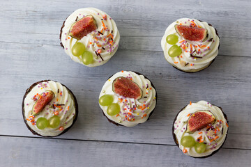 Delicious cupcakes with vanilla cream, figs and grapes.View from