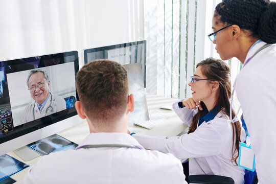 Group of interns discussing lungs x-ray of petient with covid-19 with expericed coworker from another clinic online