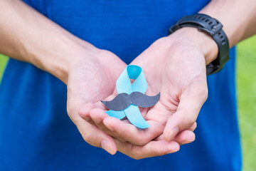 November Prostate Cancer Awareness month, adult Man holding Blue Ribbon with mustache for...