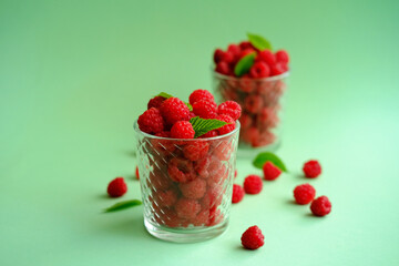 Ripe summer raspberries in glass on color background