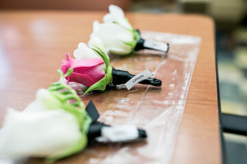 white and pink rose for a groom boutonniere at wedding with label pinned on it