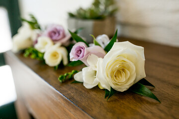 large white and purple rose groom boutonniere or corsages set on table