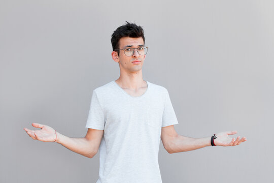 Closeup portrait of dumb clueless young man, arms out asking what's the problem who cares so what, I don't know. Isolated on white background. Negative human emotion, facial expressions, attitude