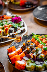 set of sushi roll with salmon, avocado, cream cheese, cucumber, rice, caviar, eel, tuna in plate on wooden table background in cafe