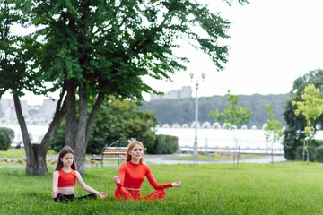 Fototapeta na wymiar woman and child do yoga in the park. summer, sun, mother and daughter, health. outdoor sports. healthy sport lifestyle. fitness, yoga