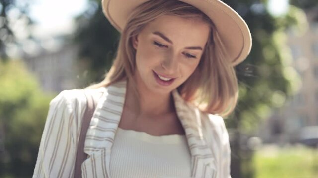 Young blonde woman using phone in city park.