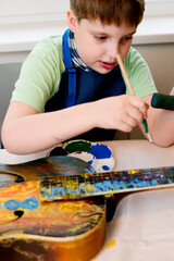 Kid have fun painting guitar. Color gouache art therapy lesion. Fine motor skills. Preschool or special needs tasks. Early education of children. Montessori methodology.