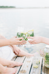 Girls holding fresh lemonade in glass. Healthy vegan lifestyle. Lemons, oranges with mint in the glass.