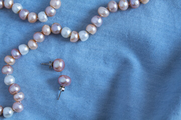 Pearl earrings and necklace on blue draped fabric