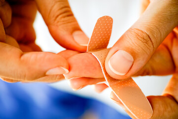 Woman putting adhesive bandage on her finger.