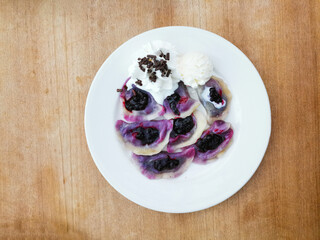 delicious sweet polish dumplings stuffed with blueberries jam and blueberries for toppings served with vanilla ice cream and Whipped cream in white plate