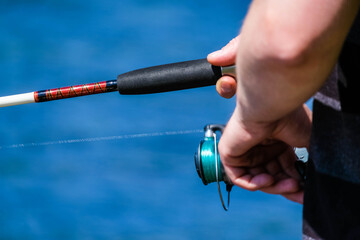 Man on the lake with fishing rod close up in hands with space for text. Fisherman close up with fishing rod, luring the fish. Men fishing with fishing tools.