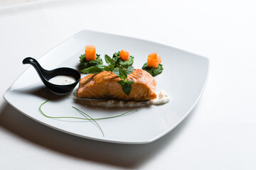 Fried salmon steaks with vegetables on white plate