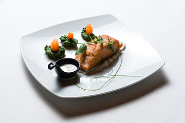 Fried salmon steaks with vegetables on white plate