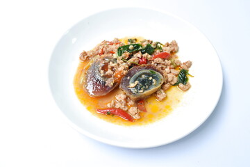 slice boiled  black preserved egg dressing spicy fried chop pork and basil leaf on plateleaf