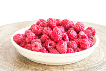 Raspberry berries in a plate on the table on a white background.