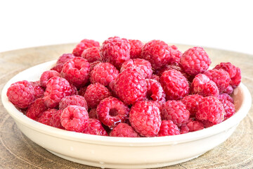 Raspberry berries in a plate on the table on a white background.