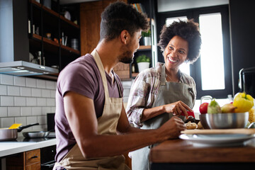 Happy young couple cooking together in the kitchen at home.