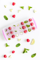 Ice tray with berries, lime and mint on white background top view