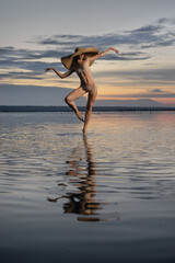 Beautiful woman in hat dancing on water