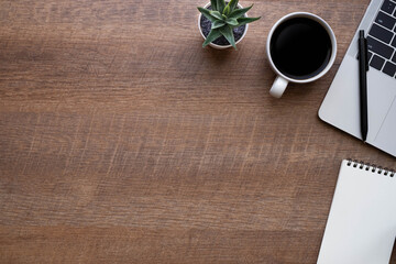 Wood office desk table with laptop, notebook and coffee cup with equipment other office supplies. Business and finance concept. 