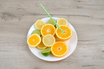 Plate with cut citrus and straw on wooden background. Healthy food concept.