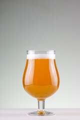 Glass of golden color beer with neutral background