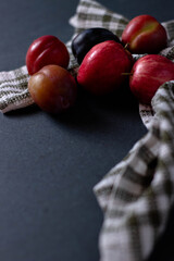 small red apples and plums on a towel on the table