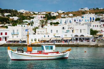 Obraz premium Greek fishing boat in clear sea water in port of Mykonos. Chora town, Mykonos, Greece