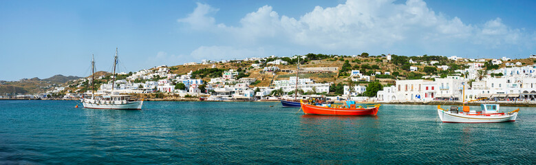 Panorama of greek fishing boats in clear sea water in port of Mykonos. Chora town, Mykonos, Greece