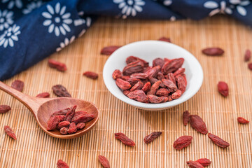 Low angle shot of a plate of goji berries placed on a bamboo mat