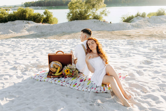 Picnic on the sand near the lake in summer. Happy young couple