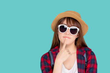 Beautiful portrait young asian woman wear sunglasses and hat having backpack smile confident enjoy summer holiday isolated blue background, tourist model girl thinking idea planning travel concept.