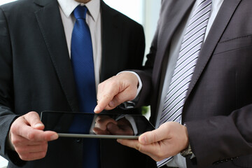 Cropped head of men in classic suits and ties are discussing work while using touchpad