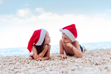 Boy and girl with the Santa hats on the beach