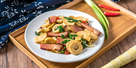A plate of winter bamboo shoots bacon on a wooden table