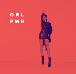 Young girl in disco clothes with raised hand stand in red light. Photo for ad, women's blog. Feminist poster. Girl power