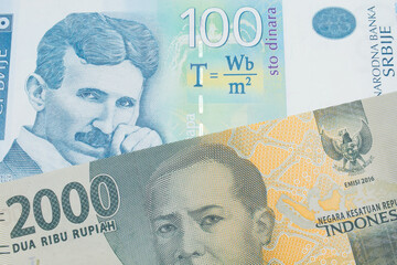 A macro image of a grey two thousand Indonesian rupiah bank note paired up with a bue and white one hundred Serbian dinar note.  Shot close up in macro.