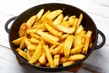 Sliced potato with spices. Cooking fried potatoes in a pan.