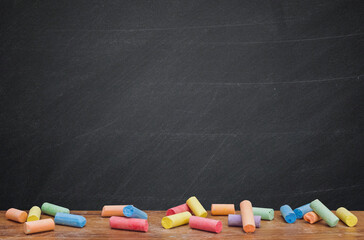 Group of colorful chalk on blackboard or chalkboard as background. School education, dark wall...