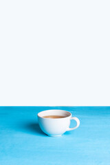 White cup of tea on a bright blue background. Space for text. Minimalism