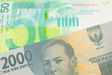 A macro image of a grey two thousand Indonesian rupiah bank note paired up with a green and white...