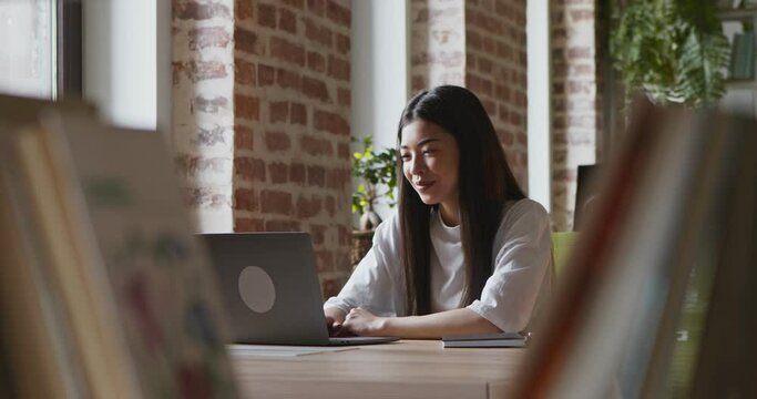 Young asian girl talking with teacher via video call on laptop