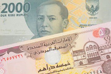 Fototapeta premium A macro image of a grey two thousand Indonesian rupiah bank note paired up with a colorful five dinar bank note from the United Arab Emirates. Shot close up in macro.