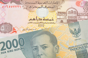 A macro image of a grey two thousand Indonesian rupiah bank note paired up with a colorful five dinar bank note from the United Arab Emirates.  Shot close up in macro.