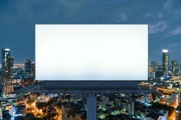 Blank white road billboard with Bangkok cityscape background at night time. Street advertising poster, mock up, 3D rendering. Front view. The concept of marketing communication to promote idea.