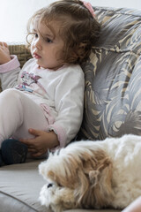 Criança sentada no sofá assistindo desenho na televisão com seu cachorro ao lado. Bebê e seu cachorro de estimação.  